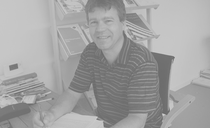 A photograph of Edgar Smeets in his office, sitting at a desk, smiling into the camera.